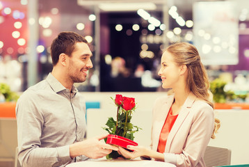 happy couple with present and flowers in mall