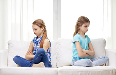 quarreled little girls sitting on sofa at home