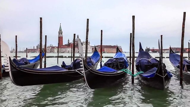 Quay at St Mark's Square with gondolas floating and the view to San Giorgio Maggiore Island in a cloudy spring afternoon.