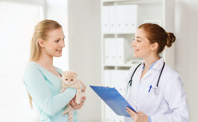 happy woman with cat and doctor at vet clinic