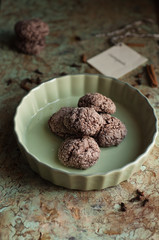 piccola teglia in ceramica con dolci aromatizzati alle spezie, cacao e caffè; altri dolci e etichetta sfuocati sullo sfondo