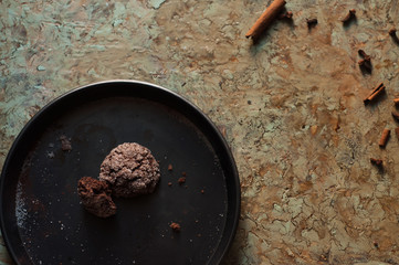 teglia nera con dolci speziati al cacao e caffè appena sfornati; fotografia zenitale con biscotto morsicato per mostrare l’interno e spezie sparse sulla base