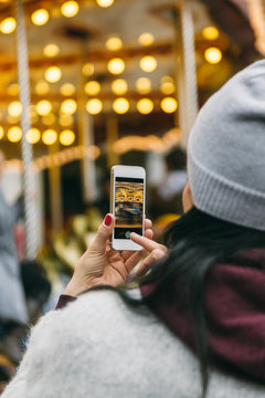 Woman Recording a Video of a Carousel with a Smartphone