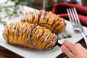Magnifying glass examining hasselback potatoes