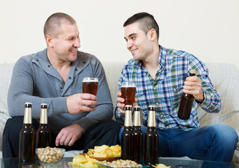 Two friends drinking beer at home