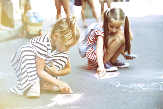 Happy active children drawing with chalk on asphalt