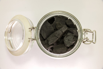 black charcoal in glass jar isolated on white background