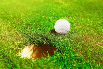 Golf ball on lip of cup on the green golf course