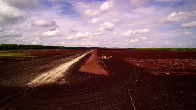 The peat field with flowers on the side. Peat (turf) is an accumulation of partially decayed vegetation or organic matter that is unique to natural areas called peatlands or mires