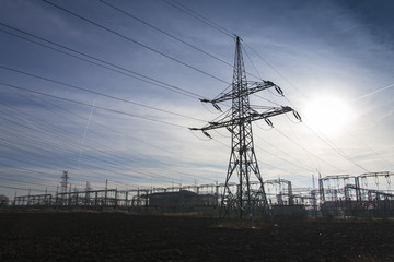 Electricity pylon from distribution power station with sun in background
