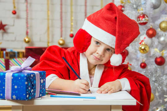 The girl with enthusiasm draws a Christmas card