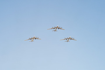 3 Tupolev Tu-95MS (Bear) large four-engine turboprop-powered strategic bombers and missile platforms fly on blue sky background