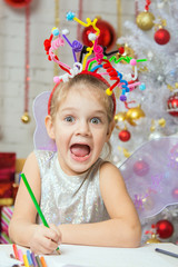 Girl with a toy fireworks on the head draws a congratulatory New Years card
