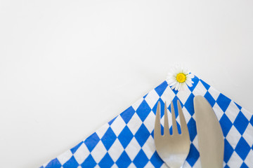 Es ist angerichtet – Essen in Bayern! Ein Gänseblümchen auf einer weiß-blauen Serviette