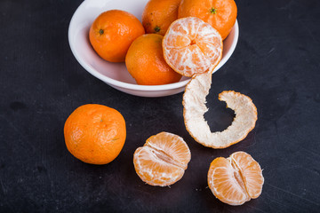 Organic mandarin oranges in white bowl on black table