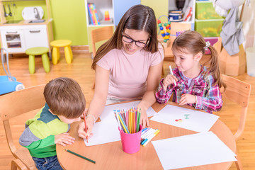 Naklejka premium Nauczyciel ładny chłopiec i dziewczynka w klasie przedszkolnej