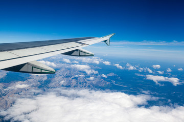 View of clouds and Rocky Mountains outside airplane window