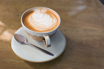 Hot art Latte Coffee in a cup and laptop on wooden table