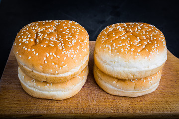 Buns with sesame for hamburger on a kitchen board