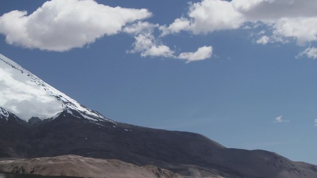 View to the Parinacota volcano snowcapped slopes with blue sky and clouds in Lauca National Park, Chile.