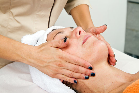 Beautiful young woman receiving facial massage with closed eyes