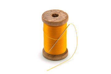Isolated wooden spool of yellow thread with a needle