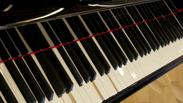 PIano keys are moving without anyone playing it. The keys are being played by no one in a grand piano