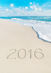 Beach with 2016 year caption on sand. Season vacation concept.