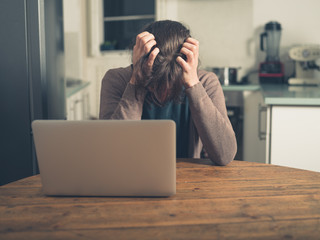 Upset young woman using laptop at home