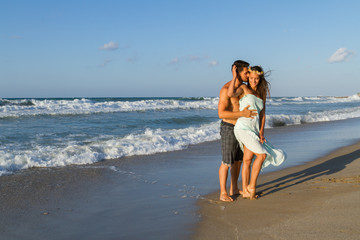 Young couple enjoys walking on a hazy beach at dusk.