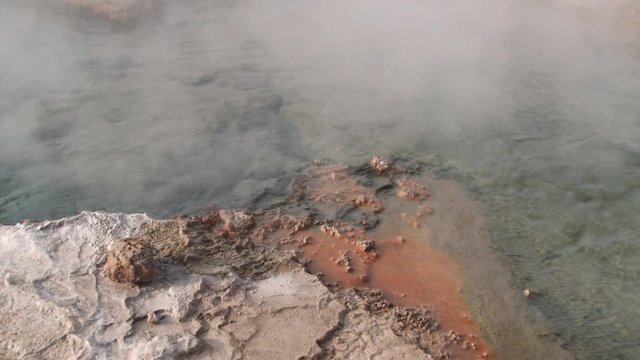 Spring with natural thermal water produces hot steam at sunrise at the famous El Tatio geyser valley at 4320 meters above sea level, Chile.