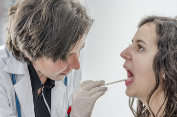 Woman doctor using a tongue depressor with girl patient.