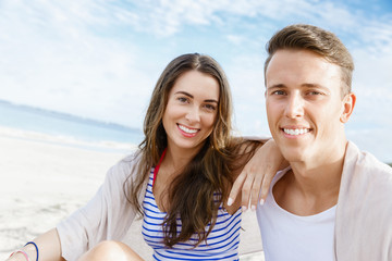 Obraz premium Romantic young couple sitting on the beach