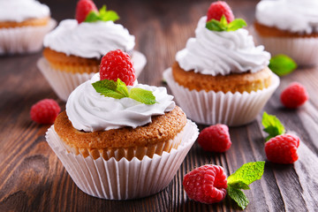 Delicious cupcakes with berries and fresh mint on wooden table close up