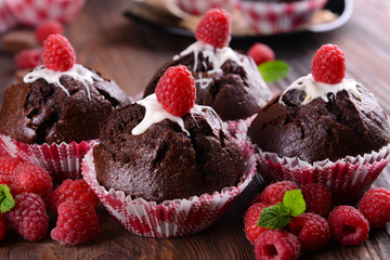 Delicious chocolate cupcakes with berries and fresh mint on wooden table close up
