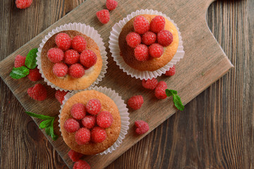 Delicious cupcakes with berries and fresh mint on wooden table close up