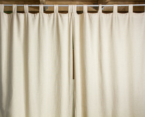 Ivory curtain hanging on a metal rod with the help hinges