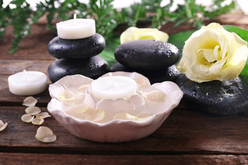 Fototapeta na wymiar Spa stones, candles and a rose on wooden background