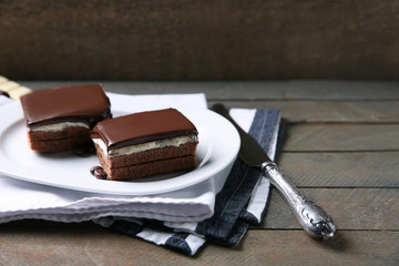 Delicious chocolate brownies on plate, on wooden background