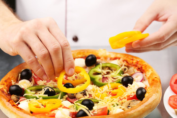 Cook making delicious pizza at the restaurant, close-up