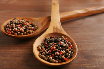 Two wooden spoons with pepper on the table, close-up