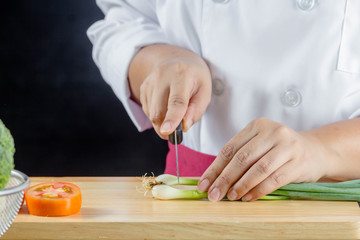 chef chopped green onions or spring onions on wooden board