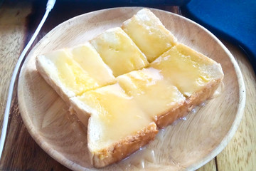 Bread toast and condensed milk on wooden plate