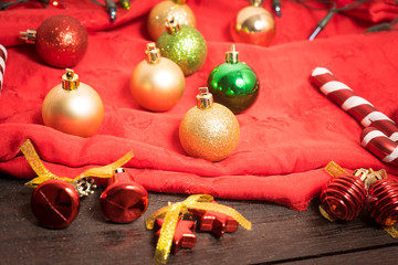 selective focus Christmas background with a red ornament, golden gift box, berries on black wood blackground still life