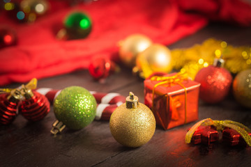 Fototapeta na wymiar selective focus Christmas background with a red ornament, golden gift box, berries on black wood blackground still life