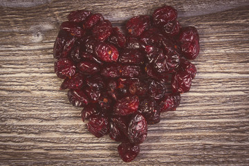 Vintage photo, Heart of red cranberries on wooden table