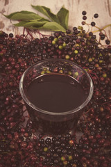 Vintage photo, Bunch of fresh elderberry with juice on old wooden background, healthy nutrition