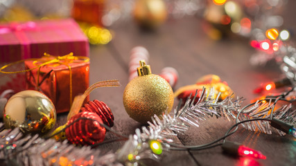 selective focus Christmas background with a red ornament, golden gift box, berries on black wood blackground still life