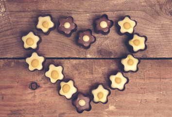 Candy in heart shape on wooden background