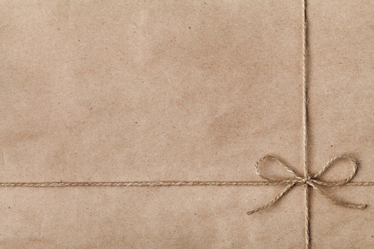 String or twine tied in a bow on kraft paper texture